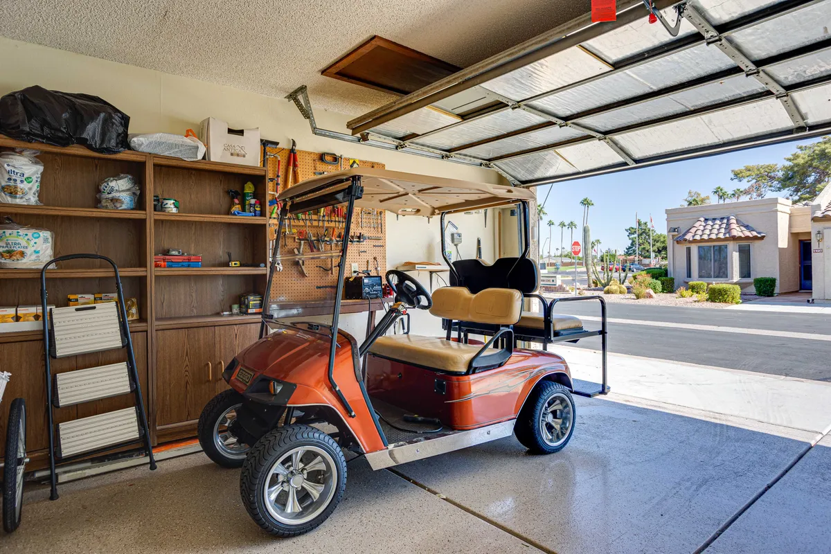 A relaxed, practical garage scene with a golf cart, visible shelving for storage, and the garage door. The image highlights the ease of accessing outdoor adventures and provides a visual cue for the garage with laundry feature and the golf cart rental option mentioned in the section.